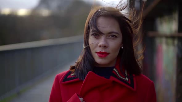Portrait of a Brunette with a Bright Make-up and Piercing on Her Face. She's Wearing a Red Jacket