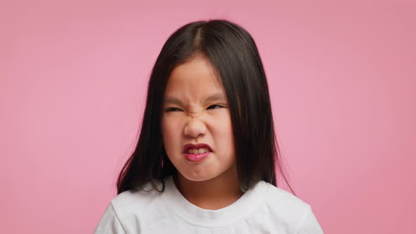 Disgusted Asian Girl Smelling Stinky Smell Frowning Over Pink Background
