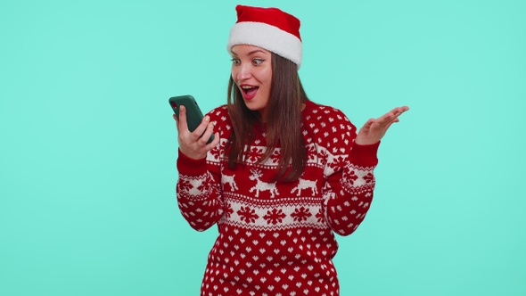 Young Teen Girl in Christmas Sweater Looking Smartphone Display Sincerely Rejoicing Win Success Luck