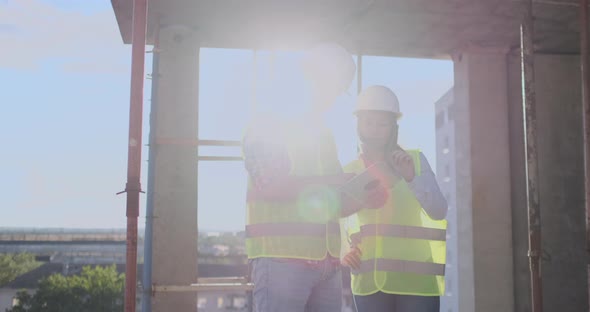 Engineers Builders Man and Woman Standing on the Roof of the Building with a Tablet Computer