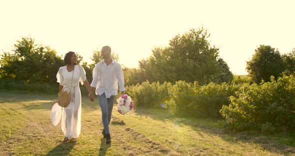 Black Newlyweds Walking with Bouquet in Nature