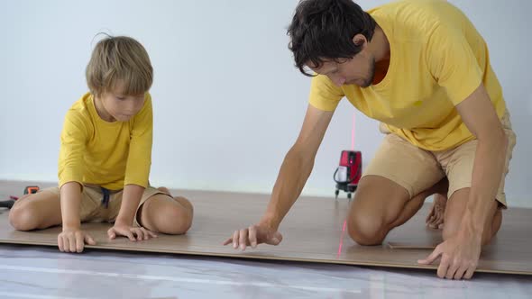 Father and His Little Son Install Laminate on the Floor in Their Apartment