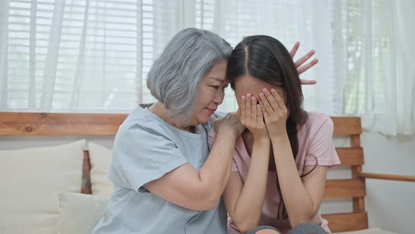 Asian older mother consoling and comforting upset depressed young girl daughter crying for problem.