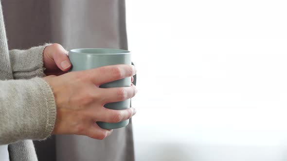 The Girl Drinks From a Mug of Hot Tea or Coffee. The Woman's Hands Hold a Cup, From Which There Is