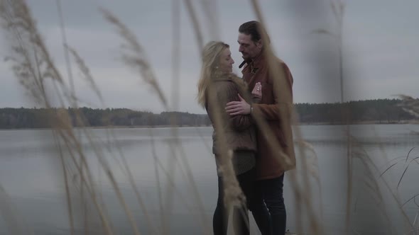 Loving Couple Hugging and Talking As Standing Behind Brown High Grass on Pier. Happy Caucasian Man