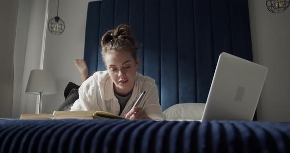 Female Student Using Laptop on Bed