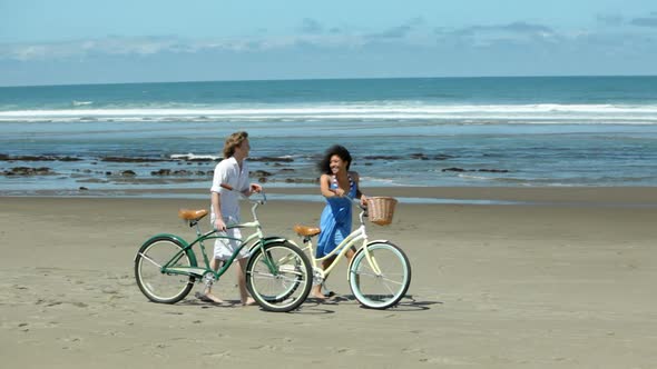 Couple walk with bicycles along coastline