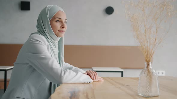 Portrait of Beautiful Young Woman in Hijab Turning to Camera and Smiling Indoors in Halal Cafe