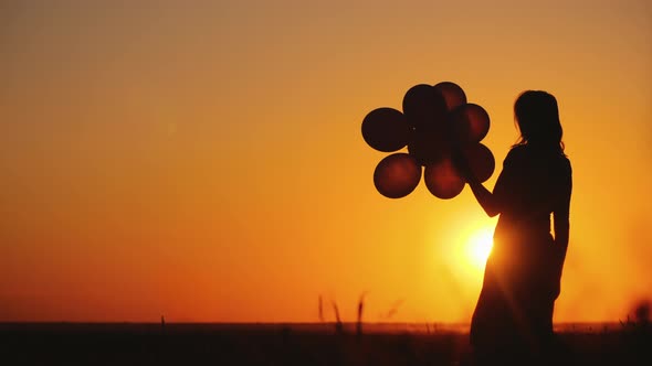 Silhouette of a Woman with Balloons at Sunset