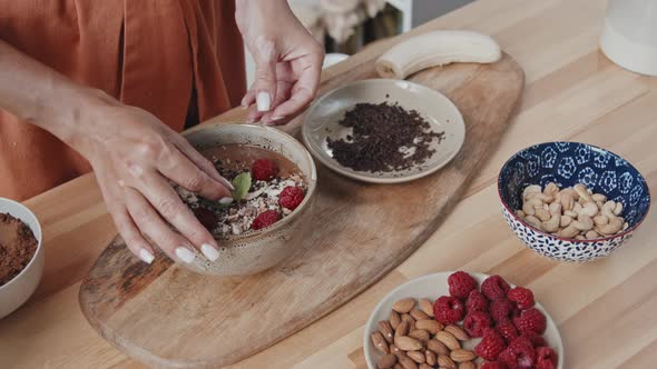 Unrecognizable Woman Adding Mint to Smoothie Bowl