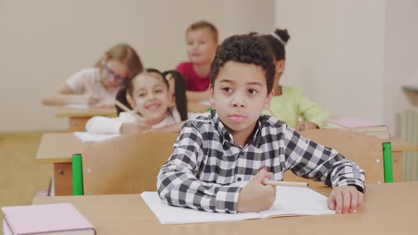 Boy Writing in Copybook in Classroom.