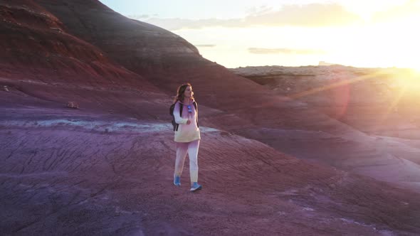 Happy Woman Walking in Colorful Red Desert at Golden Sunset with Sun Rays Flare