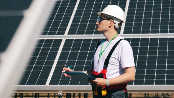 Maintenance Specialist Is Taking Notes Next To Solar Batteries