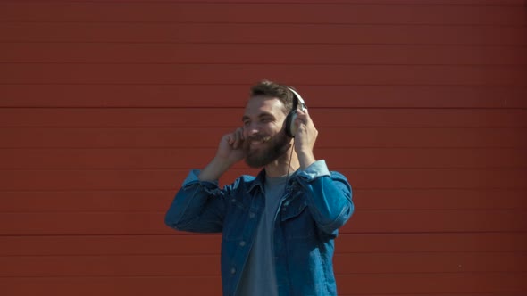 Happy Young Man with Headphones. Listening To Music and Dancing on a Red Background. Slow Motion