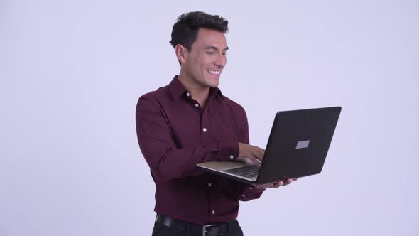 Young Happy Hispanic Businessman Thinking While Using Laptop