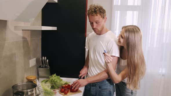 Content Attractive Young Wife Showing Pregnancy Test To Husband While Sharing Good News in Kitchen