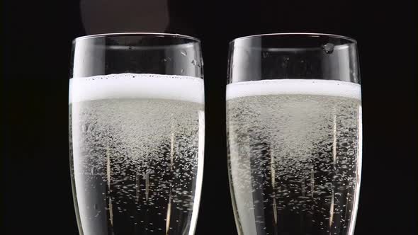 Two Transparent Glass of Chilled Champagne. Bokeh Blinking Black Background. Close Up