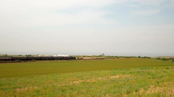 Historic Steam Train with White Smoke Rides in the Countryside