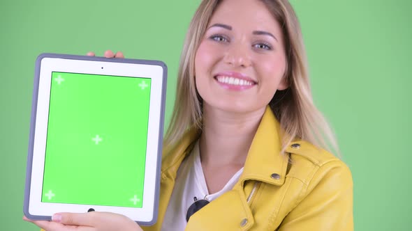 Face of Happy Young Rebellious Blonde Woman Showing Digital Tablet