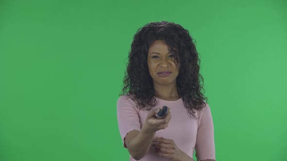 Portrait of Beautiful African American Young Woman with TV Remote in Her Hand, Switching on TV