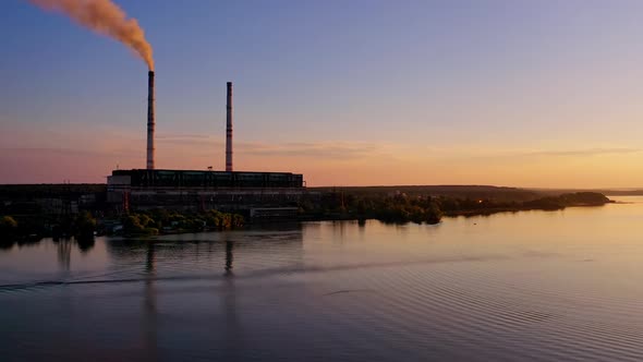 Aerial view of industry near river. Aerial drone view of factory near river during sunset