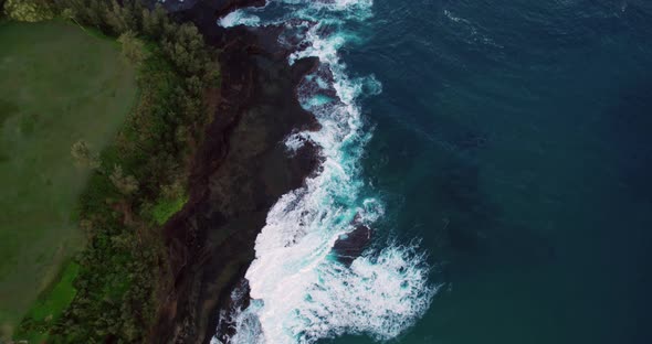 Aerial of waves crashing against rocks in Kauai, Hawaii.