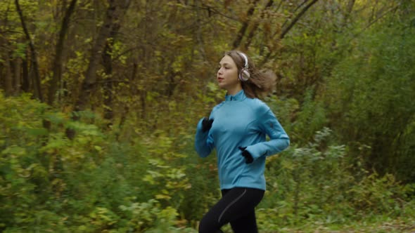 Woman jogging and listening to audio with headphones