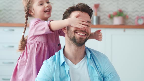 A little preschool girl covers her dad's eyes with her hands. slow motion