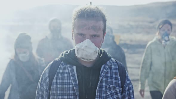 Group of young exhausted people in gas mask going through the toxic smoke 