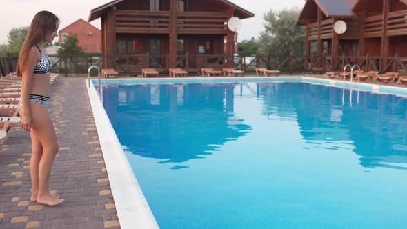 Girl in a Leopard Print Swimsuit Spends Time in the Pool Jumping Into It