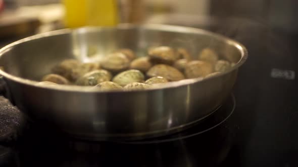 Chef cooking mussels in frying pan