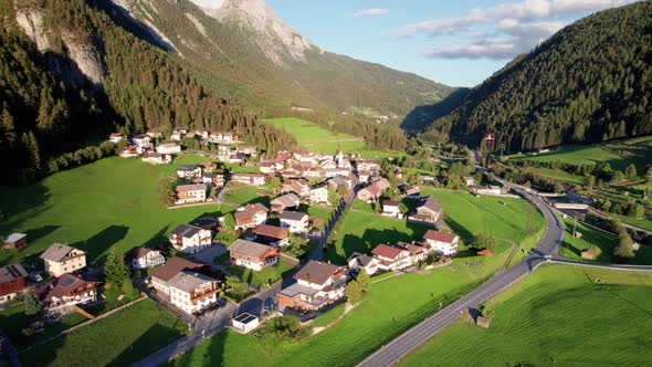 Aerial View of an Austrian Village in a Green Mountain Valley at Sunset Alps