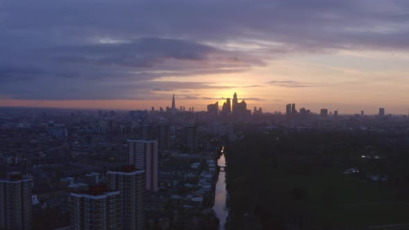 telephoto dolly back Aerial drone shot of London Canal towards city skyline at sunset