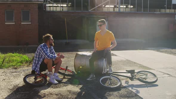 BMX riders sitting in a yard talking