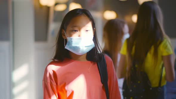 Asian Teenage Girl in Protective Medical Mask Walking in School Corridor