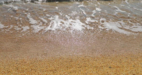 Closeup Slow Motion Footage of Beach of Gravel the Coarse Sand Waves Run on Sand Wet Stones Glint in