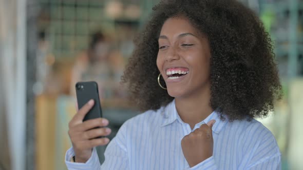 African Woman Celebrating Success on Smartphone 