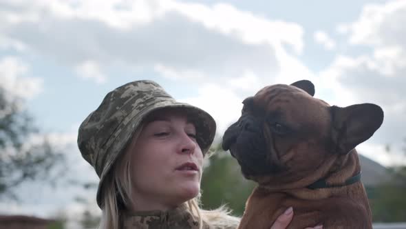 Female Soldier Holds and Hugs Her French Bulldog
