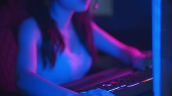 Young Pretty Woman in Glasses with Ponytails Playing Online Games in Neon Gaming Club