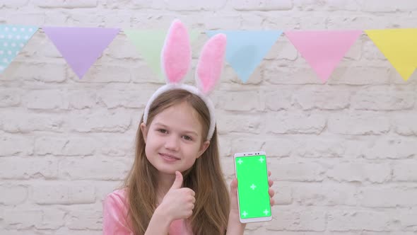 Little Girl Wearing Easter Bunny Ears Shows Phone with Green Screen