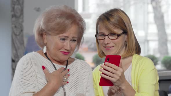 Mature Woman Showing Something on Her Smart Phone To Her Senior Mother