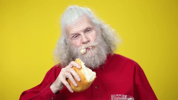 Closeup Portrait of Confident Senior Man Chewing Bread and Drinking Milk