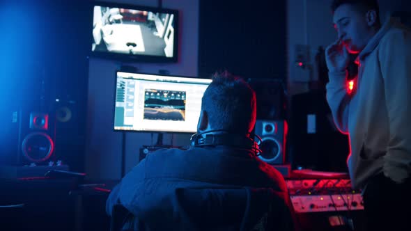 A Man Sound Engineer and Man Rapper Working on the Track in the Studio