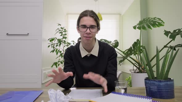 Male Teenager Talking Looking at Camera Drinking Water From Glass Using Video Communication