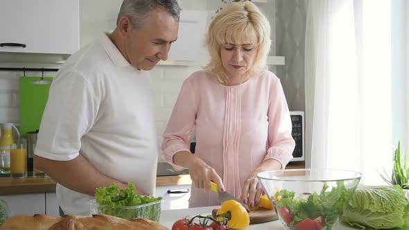 Senior Couple Preparing Salad Together in Home Kitchen