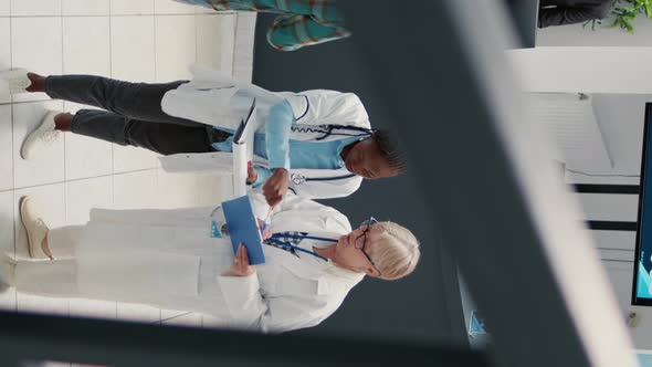 Vertical Video Senior Doctor and African American Medic Talking in Hospital Reception