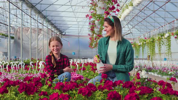 Mother Wetting His Daughter Having Fun While Working in Greenhouse