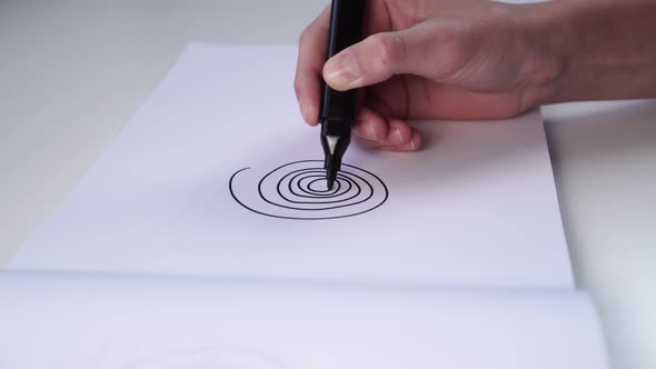 Hand of a teenager draws with felt-tip pen on a white blank sheet of an album