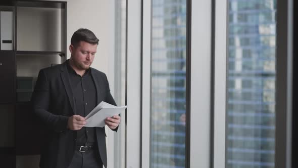 Businessman on the Background of a Skyscraper with Paper Documents