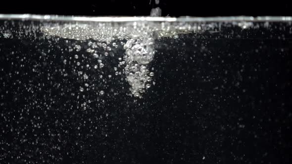 Slow Motion Stream of Water Drops Down in Aquarium on a Black Background